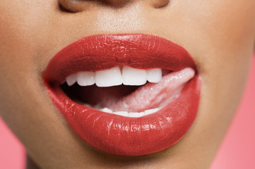 Naklejka premium Cropped image of woman licking red lipstick