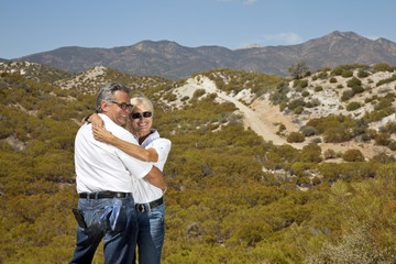 Naklejka na ściany i meble Senior couple hug with desert in background