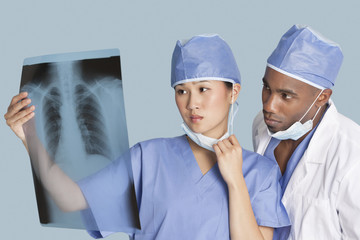 Two surgeons examining x-ray report over light blue background