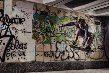Skateboarder performing grab on graffiti wall background