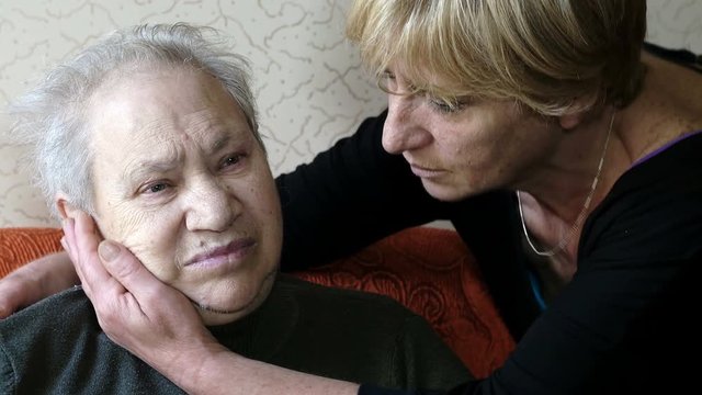 sad old woman comforted by her daughter in their house