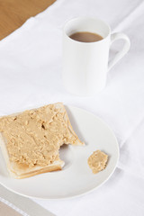 Fototapeta na wymiar Coffee mug and peanut butter on wheat bread