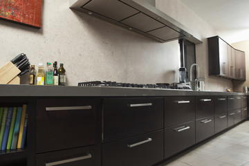 Interior of empty commercial kitchen with drawers and vent
