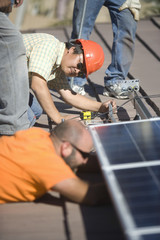 Male engineers working on solar panel at rooftop