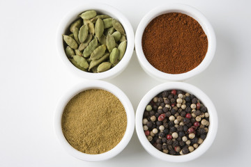 High angle view of four different types of spices in bowls isolated over white background