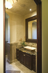 Fototapeta na wymiar View through doorway to dark brown bathroom unit with mirror frame