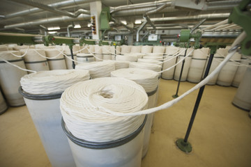 Rolls of fabric and machinery in spinning factory 