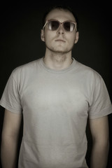 Obraz premium Portrait of handsome young man wearing sunglasses on black background