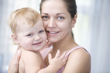 Closeup portrait of happy young mother cuddling baby girl