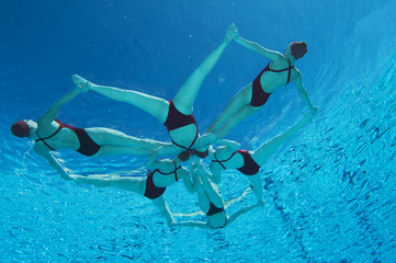 Underwater view of synchronized swimmers forming a star shape in pool