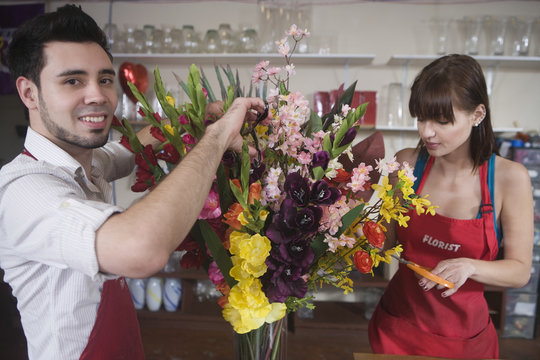 Portrait of male florist working with female colleague in flower shop