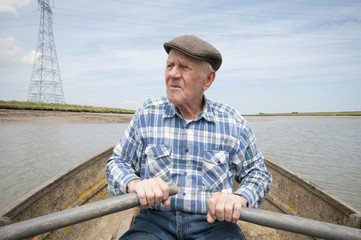 Senior man rowing a boat on a reservoir