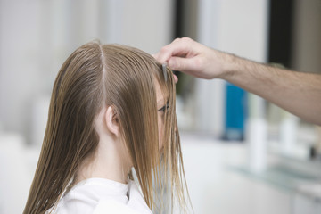 Fototapeta premium Side view of young woman getting haircut at beauty salon