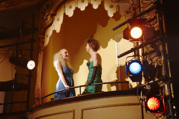 Low angle view of two young women talking in theatre box