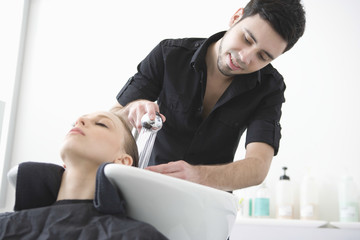 Male hairdresser washing client's hair at beauty parlor