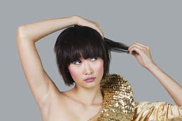 Woman in golden costume playing with hair over gray background