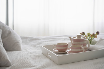 Fototapeta na wymiar Pink striped teaset on breakfast tray in bedroom