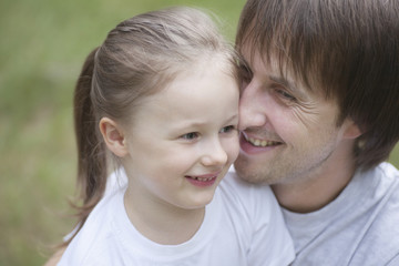 Closeup of smiling father cuddling daughter in park