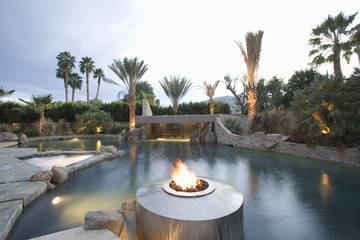 View of a swimming pool with live flame heater in foreground