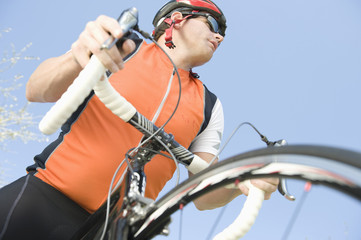 Low angle view of a man riding cycle against blue sky