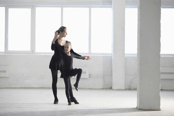 Full length of ballerina teaching young girl in empty warehouse