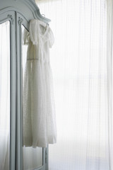 Christening gown on wardrobe at window with net curtains