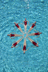 Group of synchronised swimmers forming a circle in pool