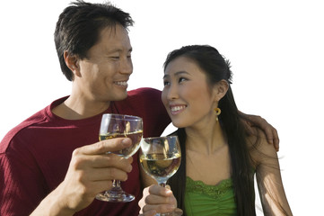 Happy mid-adult couple clinking their wineglasses against white background