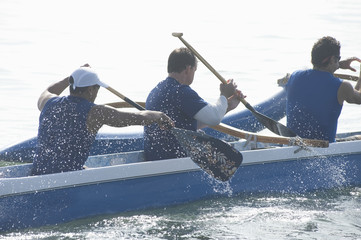 Male rowers paddling outrigger canoe in race