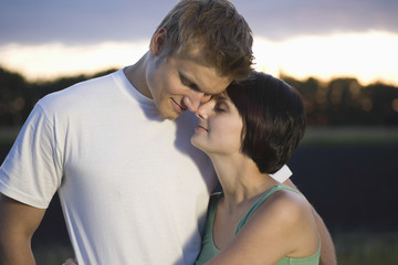 Loving young couple embracing outdoors at dusk