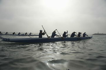 Group of multiethnic people paddling outrigger canoes in race - Powered by Adobe