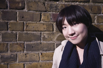 Portrait of a young Asian female against brick wall