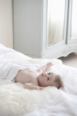 Adorable baby boy lying on fur blanket in bedroom