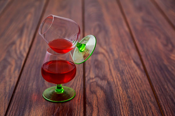 Two glasses of brandy or cognac and bottle wooden table.