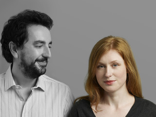 Portrait of beautiful mid-adult woman with man looking at her against gray background