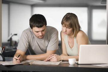 Young couple reading newspaper together at counter