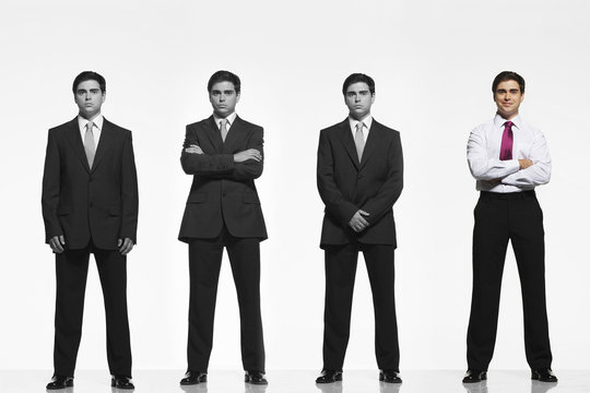 Portrait of mid-adult businessman standing out from a line coworkers against white background