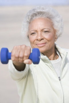 African American senior woman exercising with dumbbells at beach