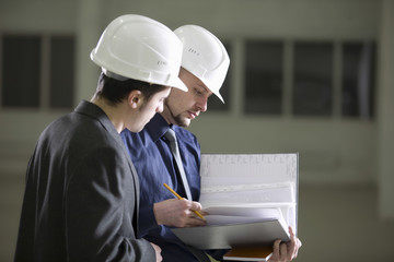 Young male architects going through file folder in warehouse