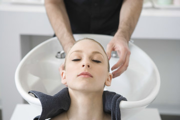 Obraz na płótnie Canvas Closeup of beautiful woman getting hair wash from hairstylist in salon