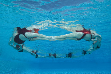 Underwater view of synchronized swimmers forming a circle in pool