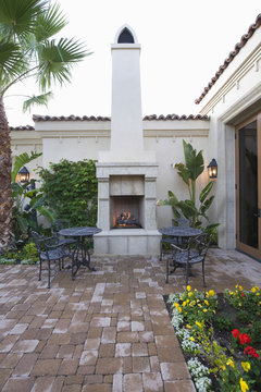 Chairs and tables at outdoor fireplace in courtyard garden of home