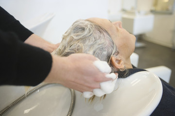 Obraz na płótnie Canvas Senior woman getting hair washed by hairstylist in parlor