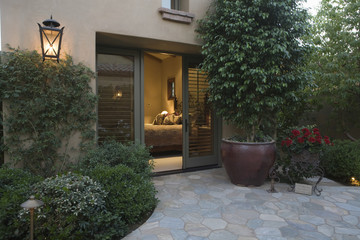 Exterior shot with crazy paving and plants with view into bedroom