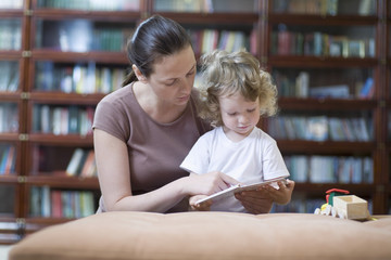 Mother and son reading book at home
