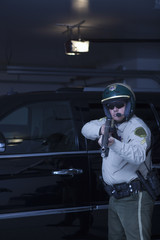 Confident policeman aiming handgun while standing in front of car