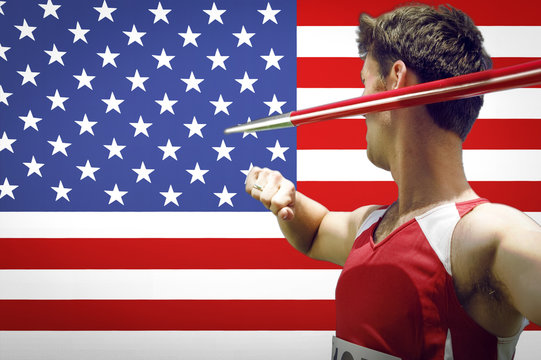 Side view of male athlete throwing javelin against American flag - Powered by Adobe