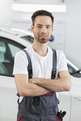 Portrait of confident maintenance engineer standing arms crossed in repair shop