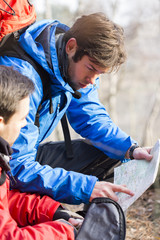 Obraz premium Male backpackers reading map in forest