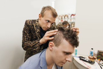 Obraz na płótnie Canvas Professional barber examining male customer's in shop